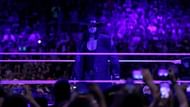 Following his loss to Reigns, The Undertaker appears in the ring in his signature black trench coat and hat.